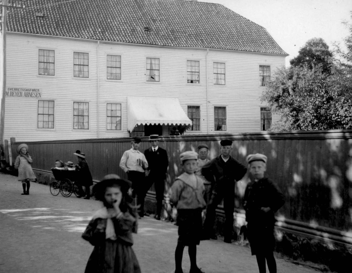 Postkort. Gateparti i Lillesand, trehusbebyggelse, barn i veien.