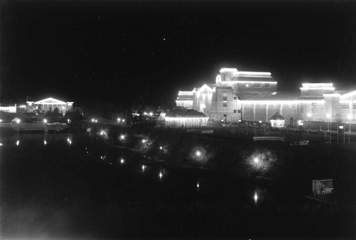 Jubileumsutstillingen på Frogner, Oslo, 1914.
Nattbilde av festbygning og industribygning. Opplyste stier langs vannbassenget.

