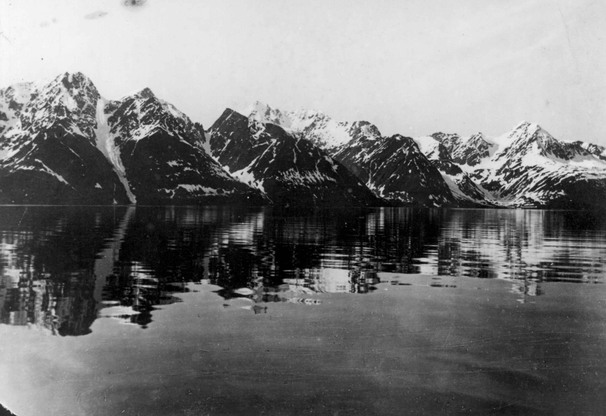 Lyngenfjorden i Troms. Snøkledte fjell og speilblankt vann.