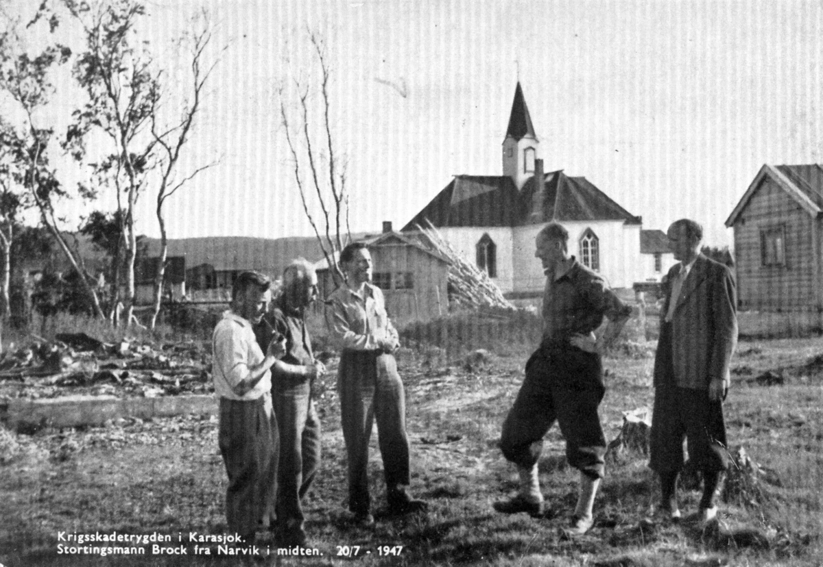 Fem personer i diskusjon, stortingsmann Brock i midten. En kirke i bakgrunnen. Karasjok 1947.