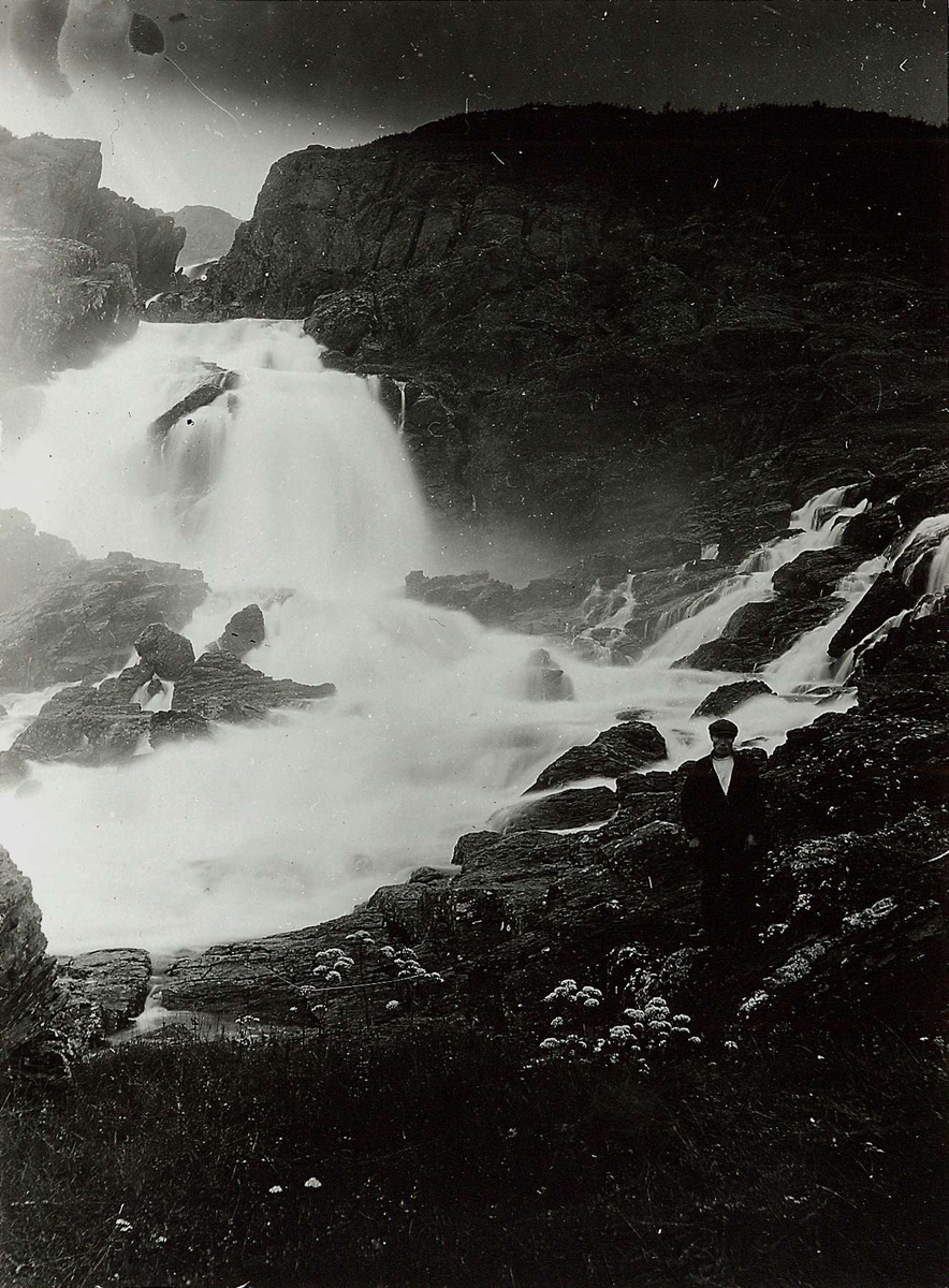 Adamsfjordfossen, Lebesby med mann i samisk drakt stående t.h.
Del av serie fra en forskningsreise i Øst-Finnmark 1909.