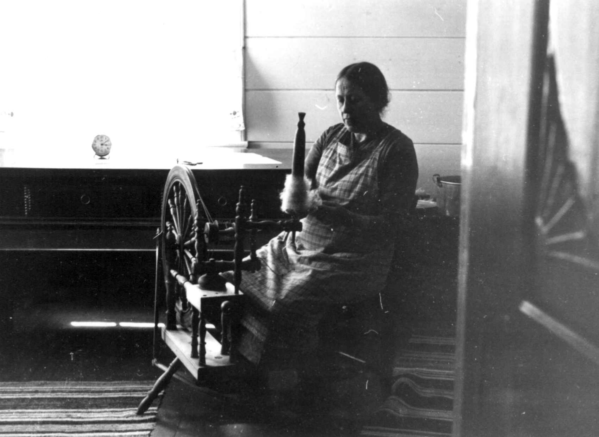 Fru Bjartland sitter ved rokken og spinner til vadmel. Bjelland, Marnardal, Vest-Agder 1939.