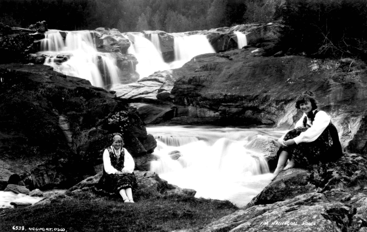 Kvinnedrakt, Nesbyen, Hallingdal. To kvinner sitter ved et fossefall. 