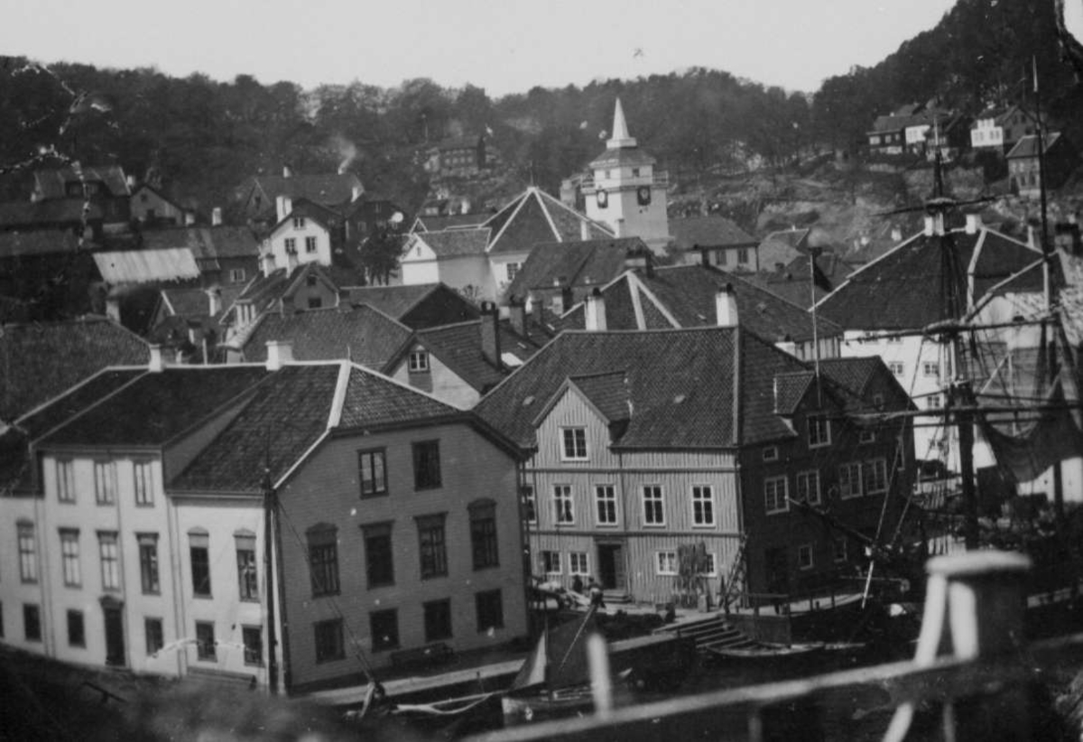 Arendal sentrum. Pollen med Tyholmen med Arendals 2.kirke,  "Åttekantkirken", reist 1836 , revet da den nåværende  Trefoldighetskirken ble reist 1888. Husene fra v. er Ellef Thomassøns Hus, nå Sjømannsforeningen Hus fra 1711, endret 1840, og Den gamle Toldboden fra 1679, endret 1807,1932. Havneliv i forgrunnen. Bildet er ant. tatt fra Batteriveien.