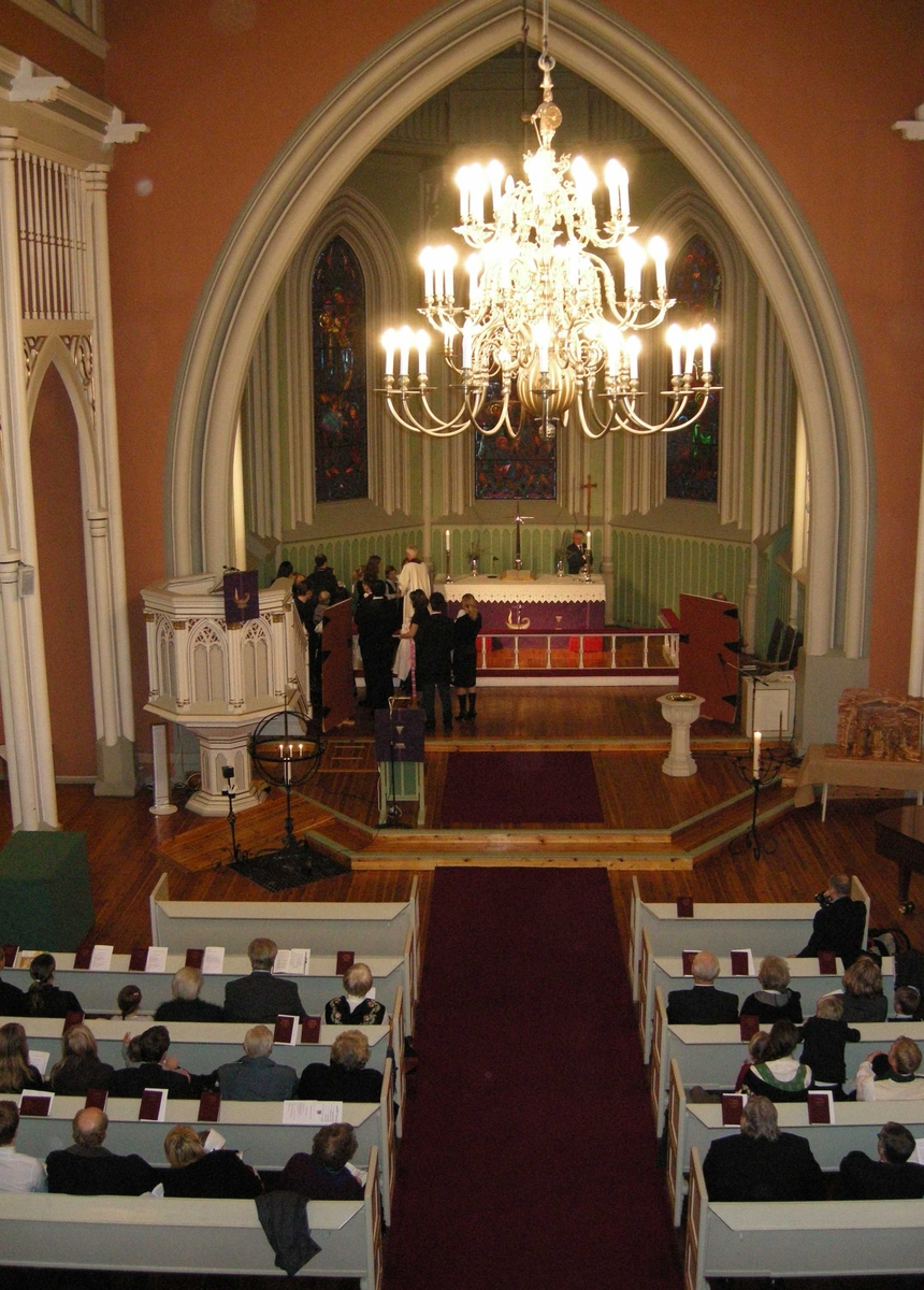 Første søndag i advent, åpning av kirkeåret. Sarpsborg kirke, Østfold, 02.12.2007. Prosesjon med kors, dåpsfølge på vei rundt alteret. I koret er dørene som er brukt i kirkeåpningsritualet åpnet. Alter, prekestol, døpefont, lysglober, kirkebenker, lesepult, lysekrone, julekrybbe og glassmalerier.