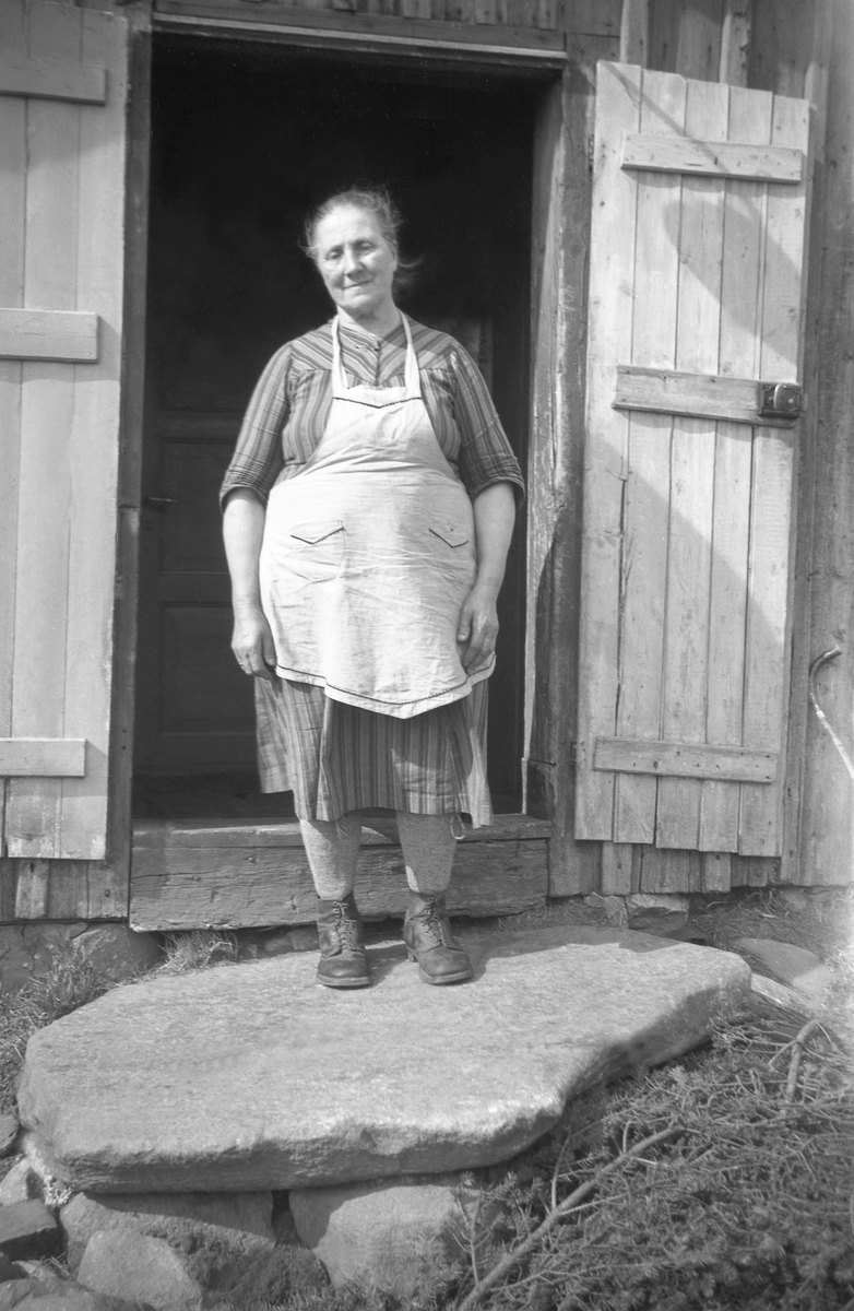 Kari Råmansett står i en døråpning til et uthus på Råmansett gård, Eggedal. Fotografert 1946.