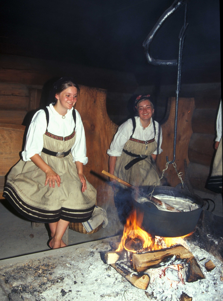 Verter i drakter ved åra i Sagastua, bygning nummer 15 på Norsk Folkemuseum, der det brygges mjød.
