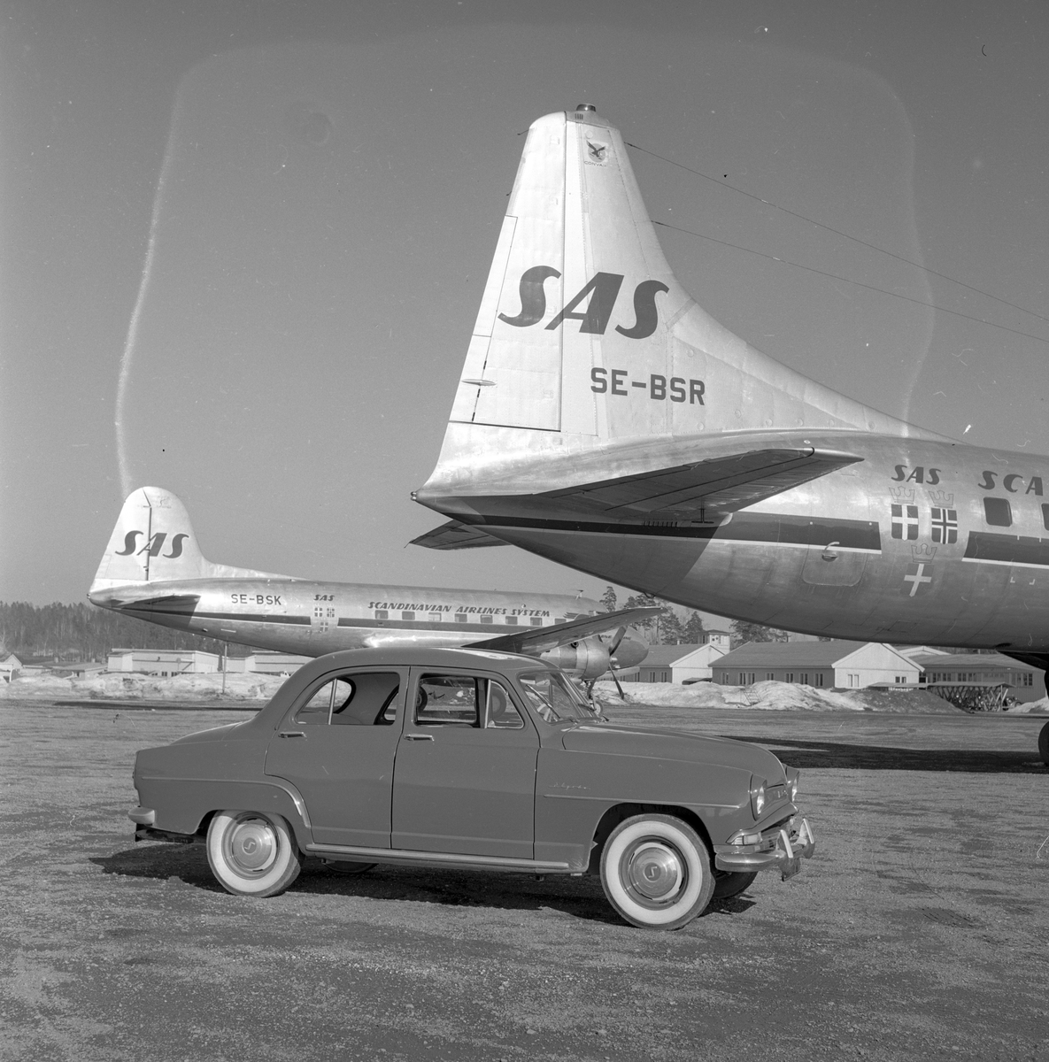 En bil av merket Simca Aronde og to SAS fly på Fornebu flyplass. Fotografert 1. april 1957.