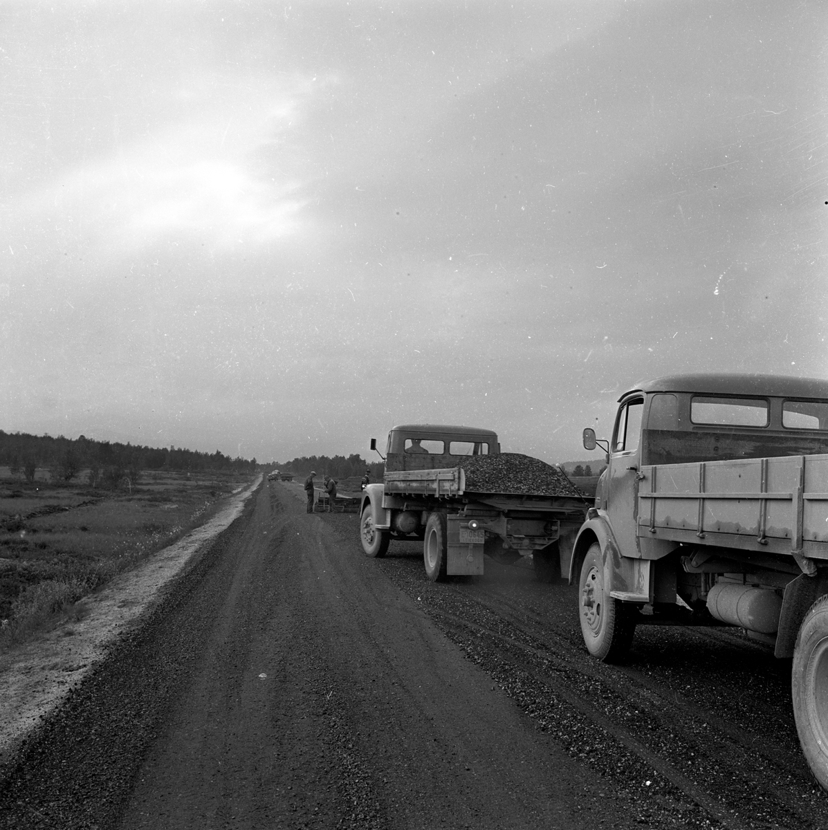 Menn alfalterere vei, lastebiler med asfalt. Fotografert august 1963..