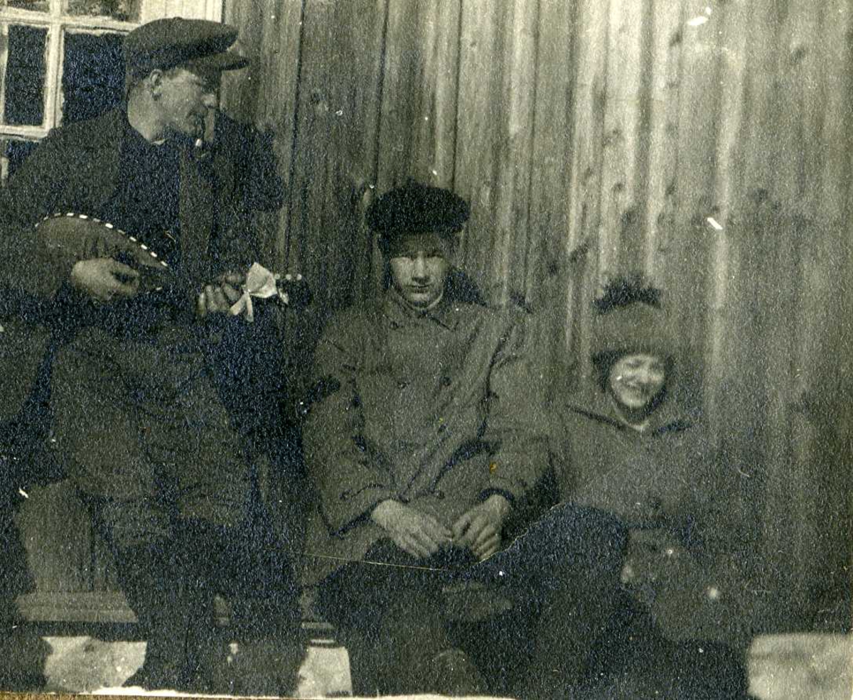 To menn og en kvinne, en av mennene spiller mandolin. Ca. 1920