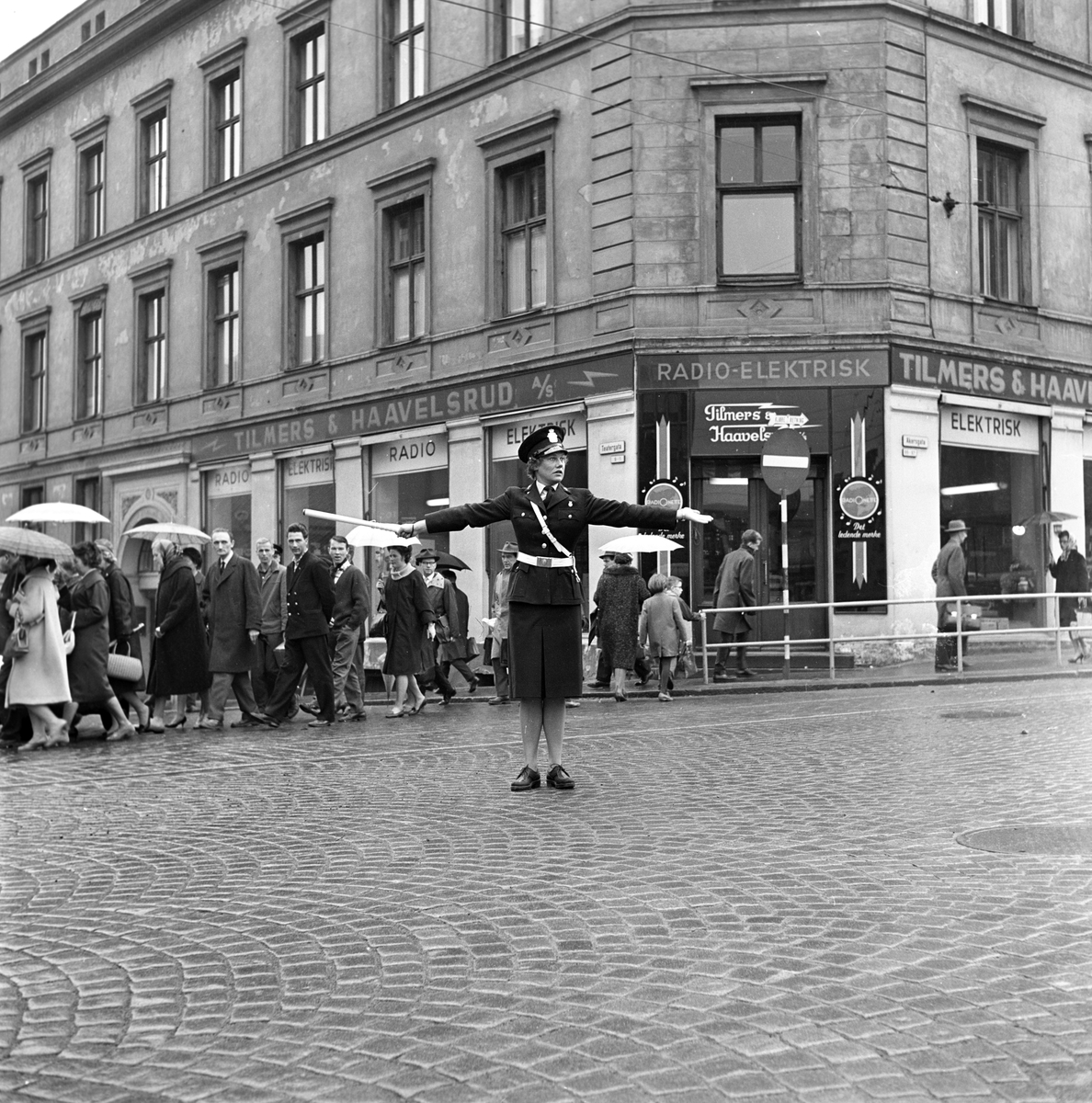 Serie. Kvinnelig trafikkpoliti. Én av dem dirigerer trafikken i krysset  Akersgata/Teatergata. Fotografert april 1962.

