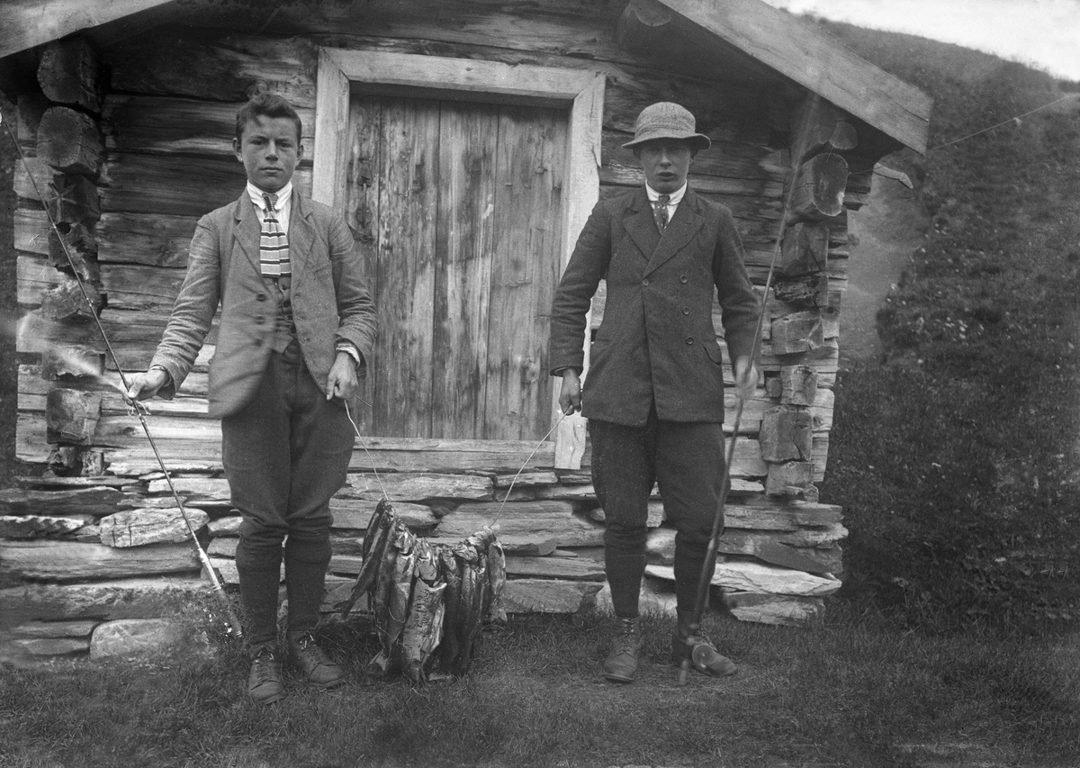 Bjarne Arentz og Leif Lunde poserer med fiskefangsten foran bur.