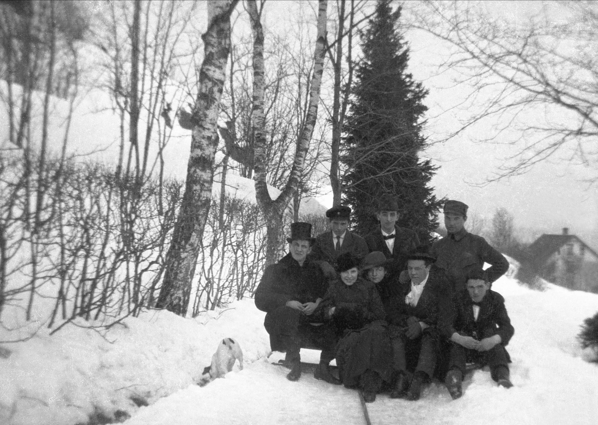 Gruppebilde tatt i snødekket hage på familien Bennetts eiendom Bergly, antagelig i Trondheim. I gruppen er til venstre Tom Bennett, med flosshat, Lillian Bennett og Fritjof Arentz.