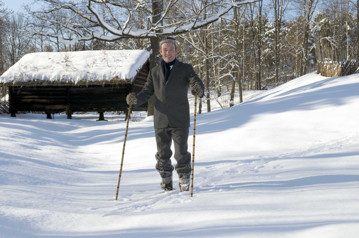 En serie med bilder av utkledd mann i klær anno 1870-1900 som går på ski på jordet bak festplassen.
Illustrasjonsfotografier.