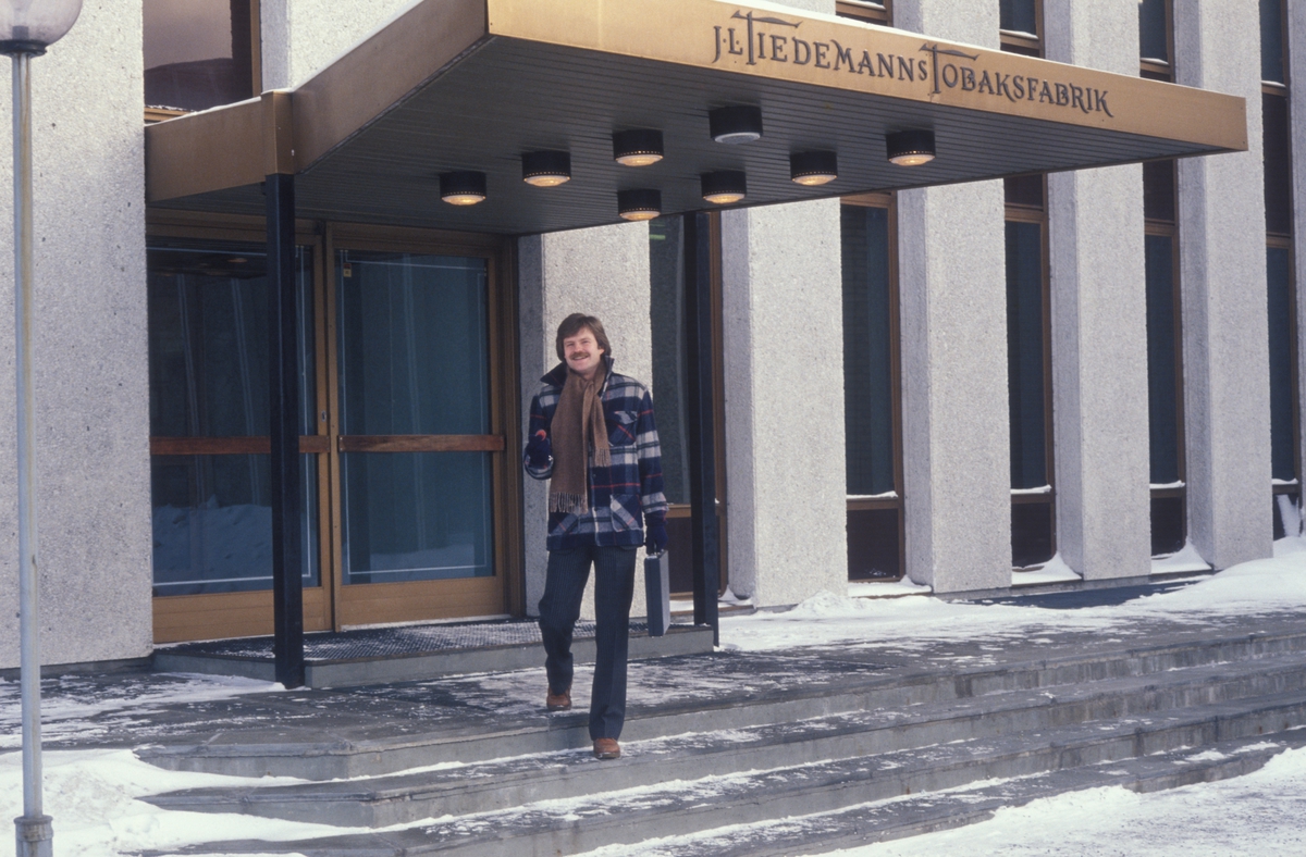 Reklamefoto av mann på vei ut fra Tiedemanns Tobaksfabrik. Reklamefoto fra presentasjon i forbindelse med introduksjon av Prince Mild i Norge i 1979.