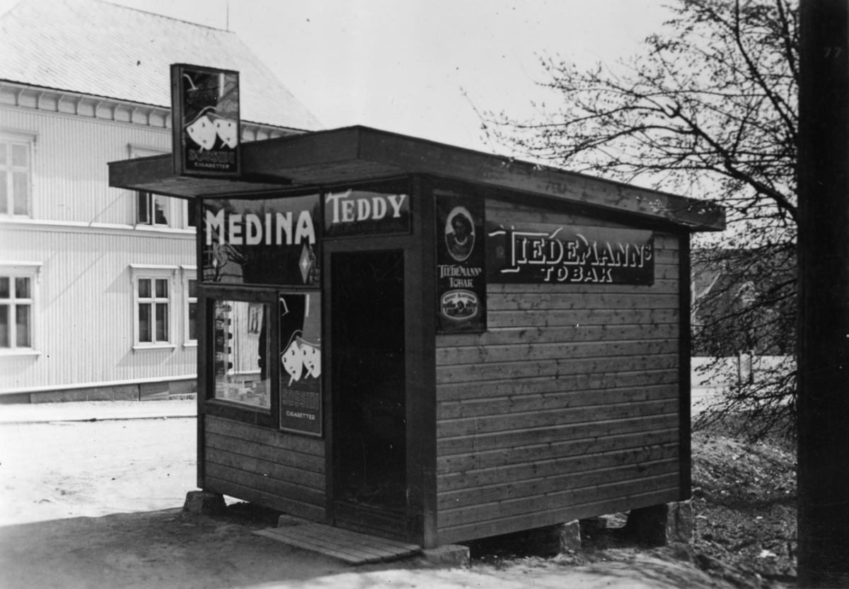 Kiosk eid av Ivar Iversen med reklameskilter fra Tiedemann i Trara i Fredrikstad 1935.