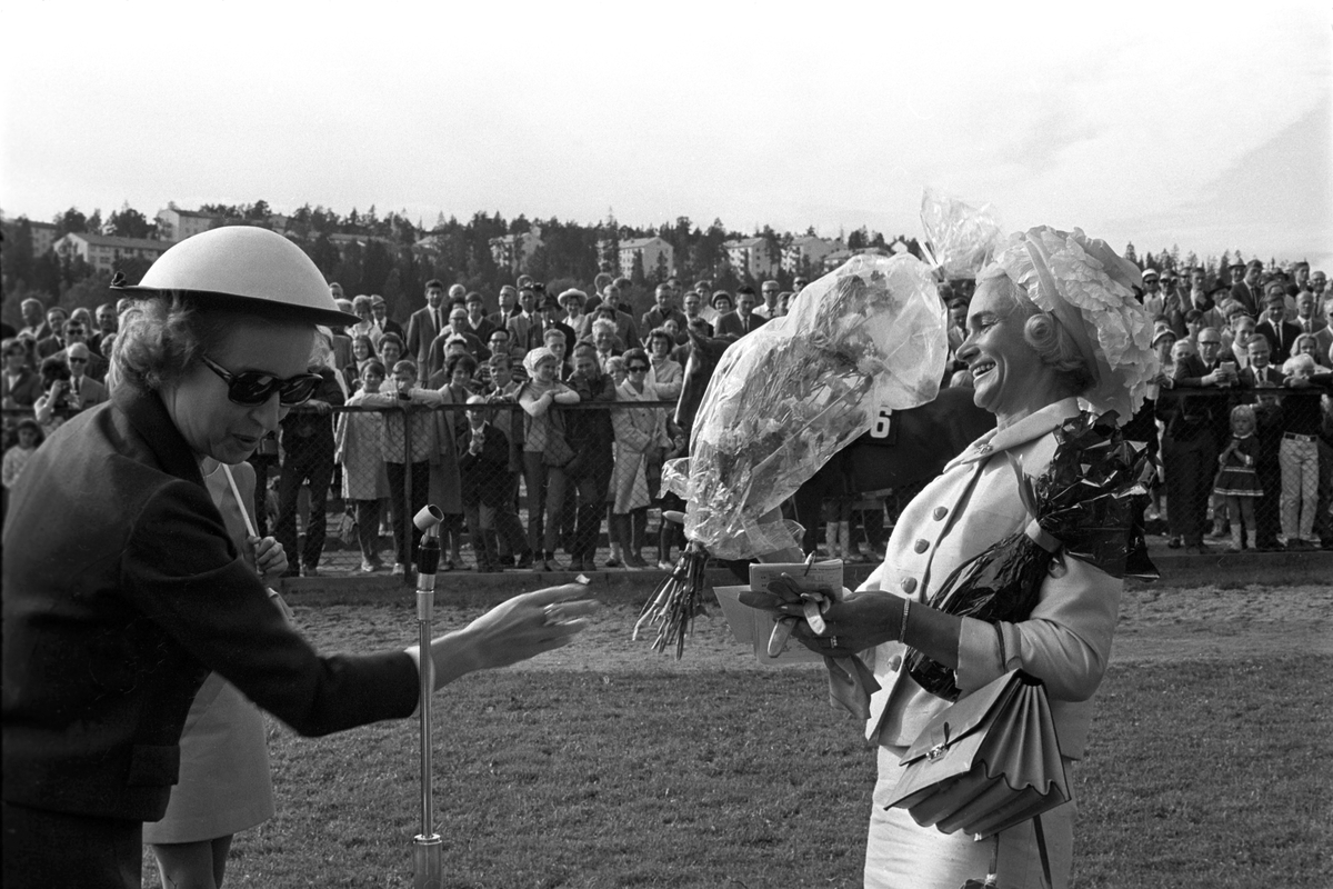 Skuespiller Wenche Foss til venstre overrekker blomster til en av deltakerne i damenes hatteparade under Norsk Derby på Øvrevoll galoppbane i Bærum 20. august 1967.