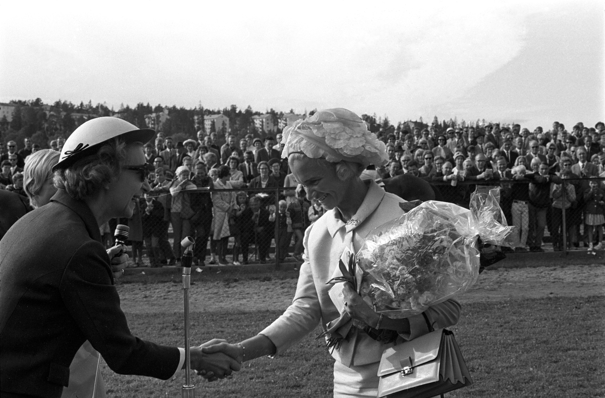 Skuespiller Wenche Foss til venstre overrekker blomster til en av deltakerne i damenes hatteparade under Norsk Derby på Øvrevoll galoppbane i Bærum 20. august 1967.