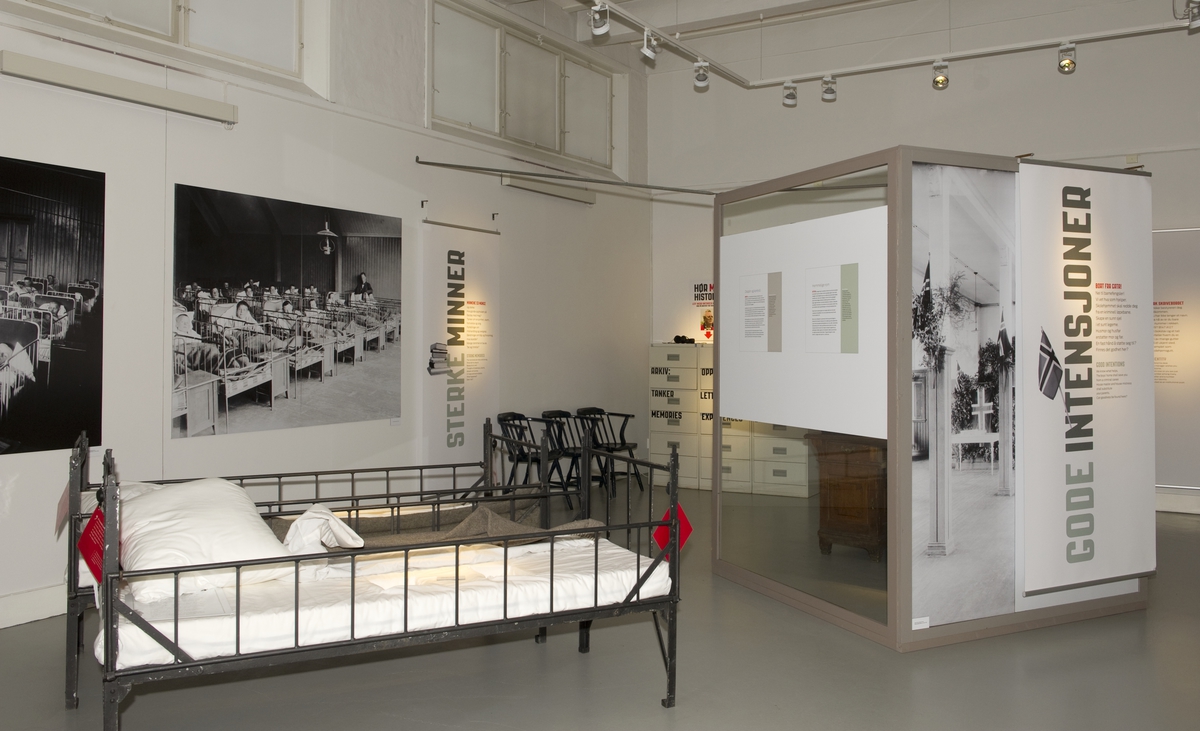 Utstillingsplakater med bilder fra Bastøy skolehjem. Sengene er rekvisitter som ble brukt i spillefilmen "Kongen av Bastøy". Fra utstillingen om Bastøy skolehjem på Norsk Folkemuseum. Utstillingen stod i perioden 15.12.2010 til 31.12.2011.