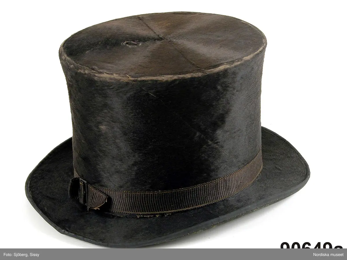 Hel mansdräkt från Österåker A.-F.

A. Hatt
B.Långrock
C.Knäbyxor
D.
E
F. Halsduk

A. Hatt, höjd 15 cm, cylinderformig av svart felb, brättet uppvikt vid sidorna och kantat med svart sidenband. Kullen något insvängd i sidorna. Kring kullen ett svart band med ett rektangulärt spänne på  vänster sida. Svettrem av rött skinn, foder av papper, tryckt med silverfärg.
B. Långrock
C. Knäbyxor längd 79 cm, av sämskat renskinn, midjegjord och smal lucka med 4 kullriga mässingsknappar, 2 fickor vid sidan om luckan. Knäsprund som knäpps med hakar och hyskor, knälinningar som knyts med smala skinnremmar.
/Berit Eldvik juni 2005
F. Halsduk, avklippt tresnibb av yllemuslin. Klippt av ett större halskläde. Grålila bottenfärg med tryckt mönster i rött, grönt och gult på utsparad vit botten, gles lila yllefrans. Fållad med tråckelstygn. Stämpel i svart i ena hörnet, svårläst men troligen: Göteborg 184?.
Viks till smal remsa, vid påtagningen läggs mitten af halsduken över strupen, ändarna tas i kors i nacken, och knyts sedan fram.
/Berit Eldvik 2010-01-08
