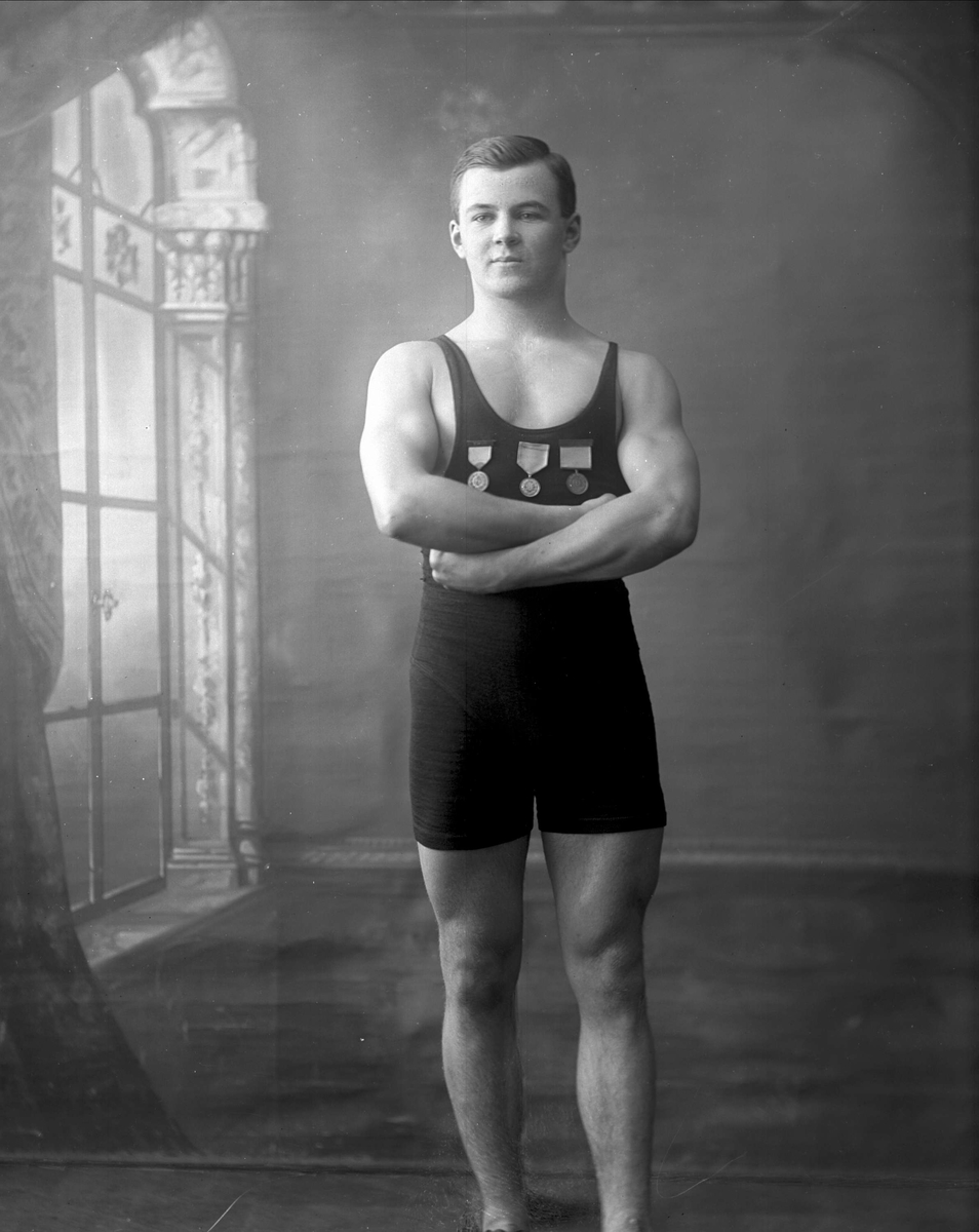 Portrett, mann i bryterdrakt med medaljer. Frydenlund.