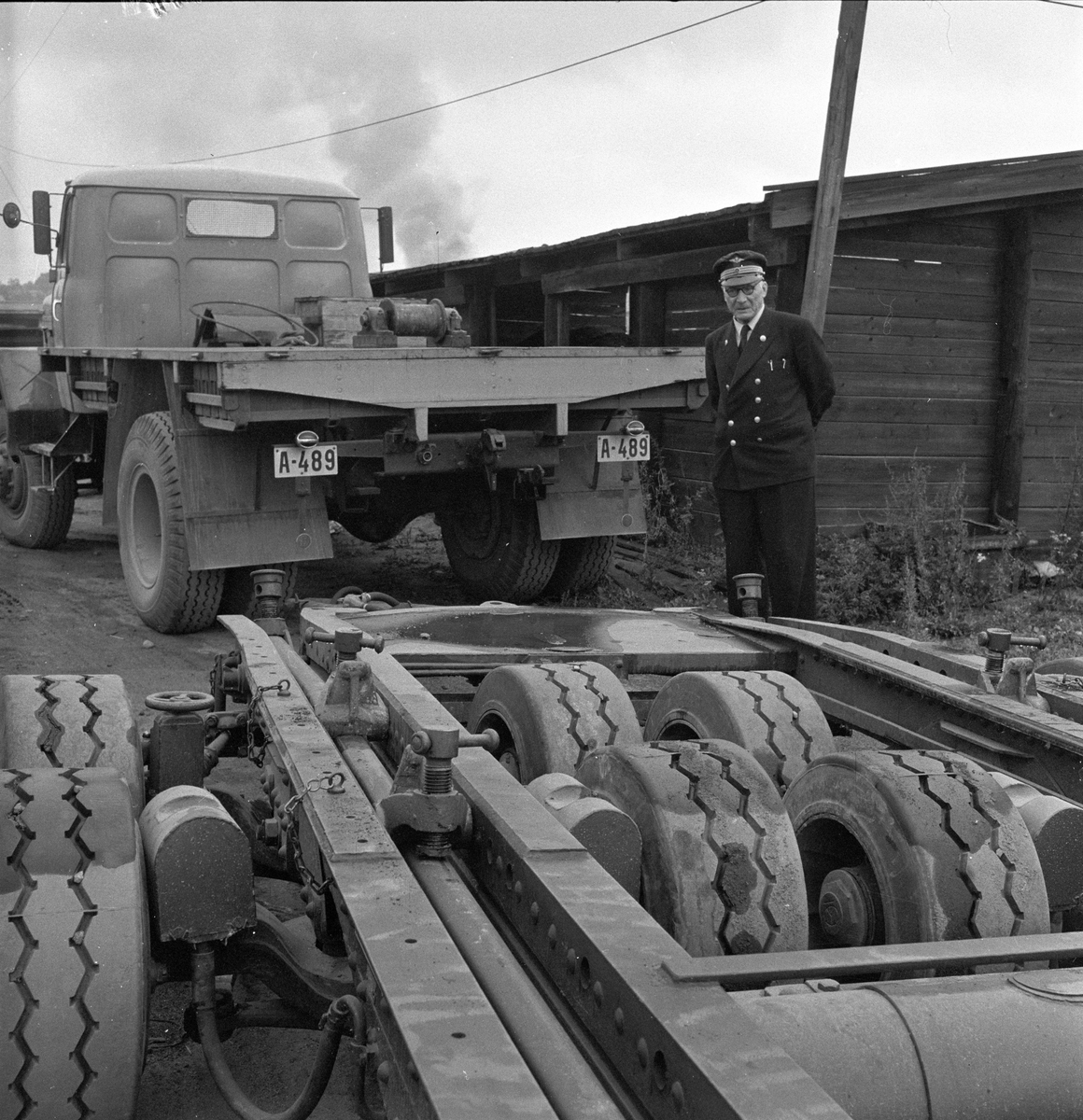 Lastebil og en spesiell tilhenger med ekstra hjul. Uniformert jernbanefunksjonær. Sept.1956.