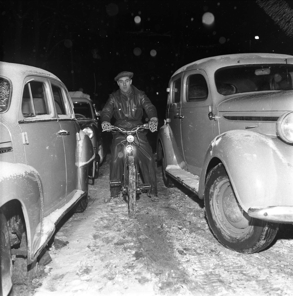 Opel Kaptein 1951-53 til venstre, og Plymouth 1937-38. Bilene står i kø, syklisten kommer frem, Oslo, 20.12.1958.