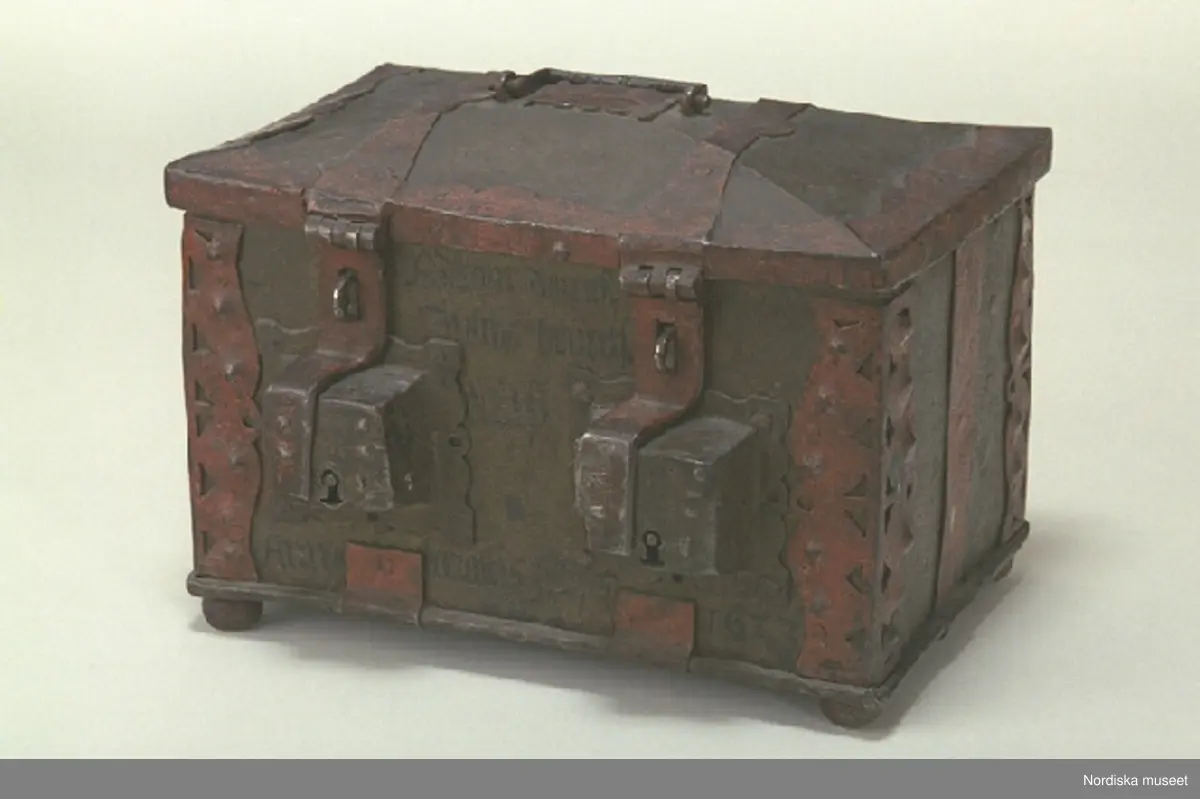 Huvudliggaren;
"a-c, Skrin, som tillh. hovslagarämbetet i Stockholm, dat. 1623. Av järnplåt m. rödmålade beslag och 2 nycklar; rekt. med fällock. fr. hovslagarämbetet i Stockholm 1868. 
a) skrin, b) nyckel (L 9 cm), c) nyckel (L 7,8 cm). 
Från Statens historiska museum 1925.

Inventering Sesam 1997-1998:
B 31, Djup 23, H 23 cm
Skrin (a), rektangulärt, med kupigt fällock, av järnplåt. Järnband fästade runt botten. Järnplåtarna ihopsatta med nitar på gavlarna.
Beslag med utstansad dekor runt hörnen.
Fasat lock med beslag runt kanterna, två bandgångjärn fästade på utsidan samt med gångjärn även vid framkanten där två låshaspar sitter.
Två utanpåliggande lås på framsidan, låses med låshasparna samt nycklar som nu saknas (har antagligen varit märkta b och c).
Skåra mitt på locket, att lägga mynt i, läderbit fästad runt öppningen på insidan, beslag på ovansidan.
Bygelhandtag fästat i märlor på locket.
Utvändigt målat i brunaktig färg, otydlig inskrift i svart på framsidan samt årtalet " 1623 ", beslagen målade i rött. Skrinet står på kulfötter, med rester av röd färg.
Från Hovslagarämbetet i Stockholm 1862.
Agnetha Blomberg 1998