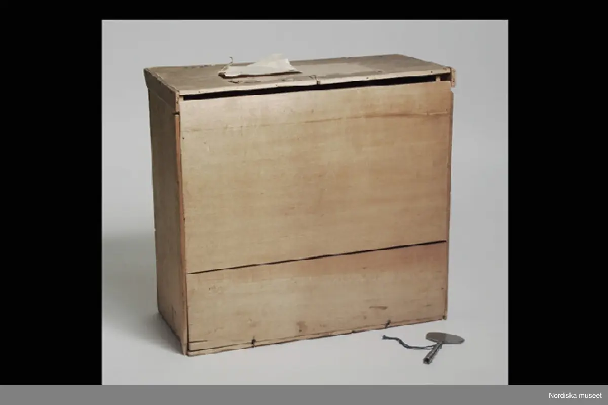 Inventering Sesam 1996-1999:
a+) Mekanisk leksak L 28 cm, B 12,5 cm, H) 45,5 cm
b) Nyckel L 10 cm
c) Originalförpackning L 37 cm, B 17 cm, H 35 cm
a+) Equilibriste ¿ Mecanique (mekanisk balanskonstnär) bestående av clown av massa (papier mach¿?), med rosa sammetsjacka och blårutiga byxor, stående på grönlackerad vagn av metall med tre hjul. På näsan har clownen fäste (spets) på vilken kan fästas. På vagnen olika fästen (bl a två svärdsskidor) för olika lösa attiraljer: Stege med docka i röd sidenjacka och beige huvudbonad, stol (delar saknas) av trä med gul sits och stående på sitsen liten docka med blå jacka, tvådelad flaggstång med grön/vit och röd/vit tvåuddiga flaggor, metallten med klocka och halvmåne i gulmetall med bjällor, Svärd av gulmetall (har ursprungligen trol. funnits två svärd)
Undertill på vagnen finns ett fjäderverk som driver vagnen frammåt och får fästet/spetsen på clownens näsa att snurra. Enligt äldre kat.kort driver fjäderverket även speldosa (?). På spetsen på clownens näsa kan de olika lösa attiraljerna fästas.
b) Nyckel, av vitmetall, ovalt huvud utan hål.
c+) Originalförpackning, enkel, av obehandlat trä, Stor lucka framtill, lock ovanpå. Enligt äldre kat.kort skall det ursprungligen ha suttit ett reklamkort på locket, vilket det nu bara finns reser kvar av.
Har tillhört brukspatron Edv. Otto Benedicks (1818-1872), Gysinge, Gästrikland. 
Leif Wallin feb 1998