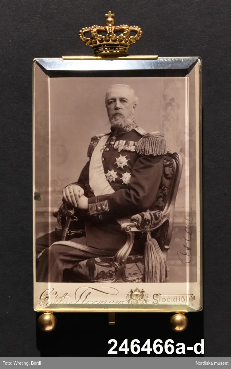 Huvudliggaren:
"a-d, fotografi, Oscar II i uniform, signerat 'Oscar', stämplat 'Gösta Florman Stockholm'; på baksidan: 'Erhöll jag i Hessleholm den 12 sept. 1899 af H.Majt efter manöverns slut vid hvilken jag var kommendant i högqvarteret.'. Med tjockt glas [b], extra pappskiva och förgylld bordsram med kunglig krona.
Gåva 19/5 1953 Friherinnan Louse Leuhusens f, Palmstierna, dödsbo. Stockholm."