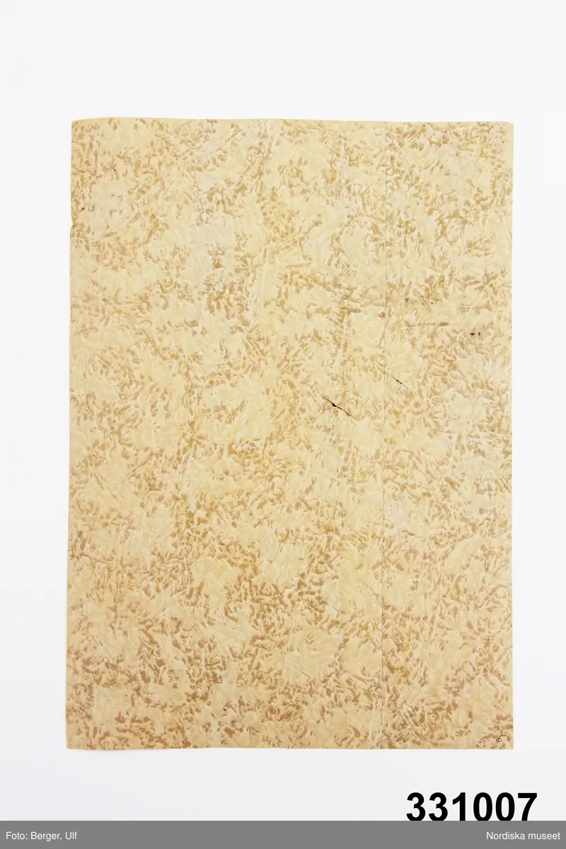 Tapetprov, papper. Beige/brun flammigt mönster.
På baksidan avtryck av underliggande tapet.
/Leif Wallin 2011-07-18