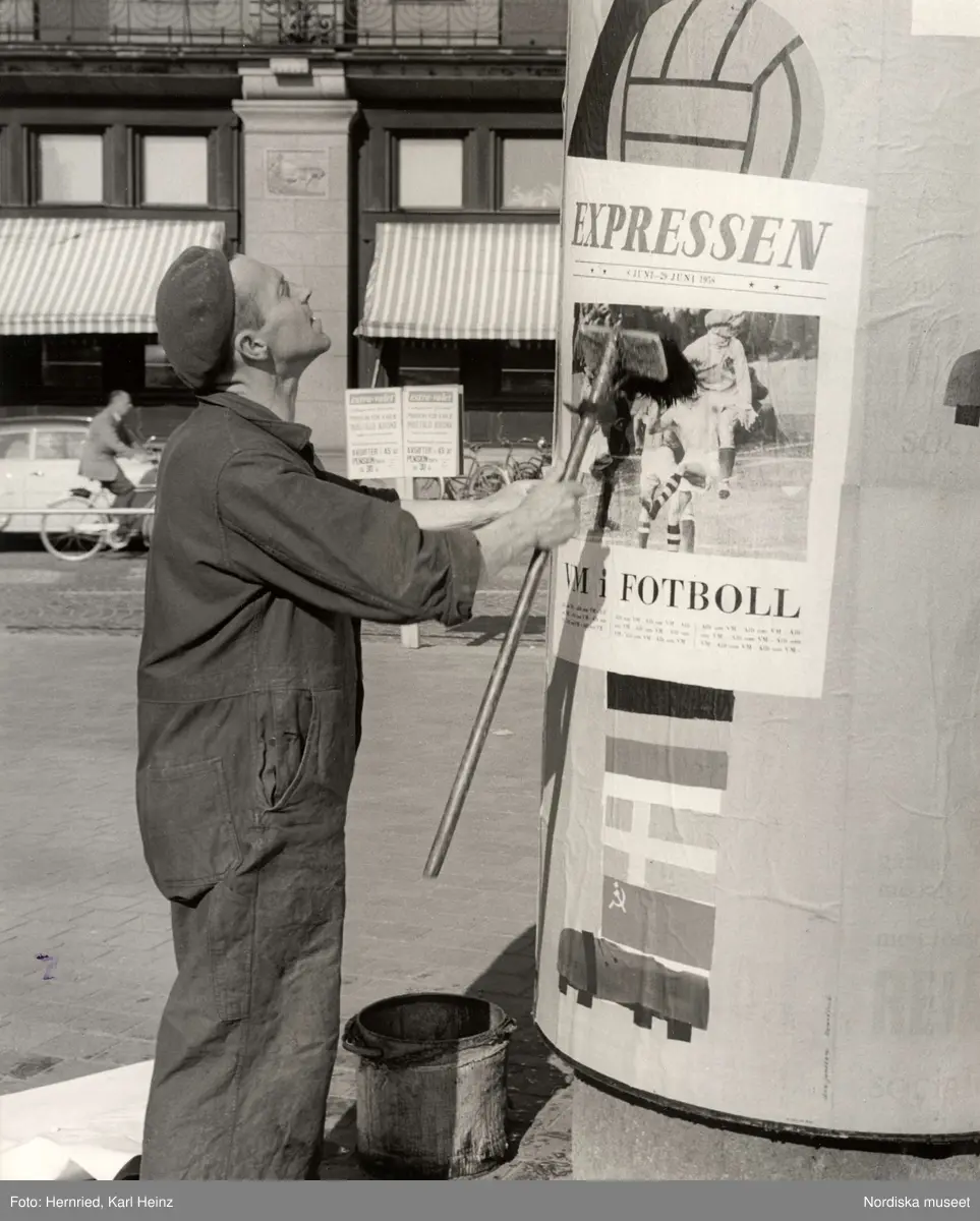 Man klistrar upp reklamaffisch på pelare. Expressens reklam för VM i fotboll 8 JUNI - 29 JUNI 1958
