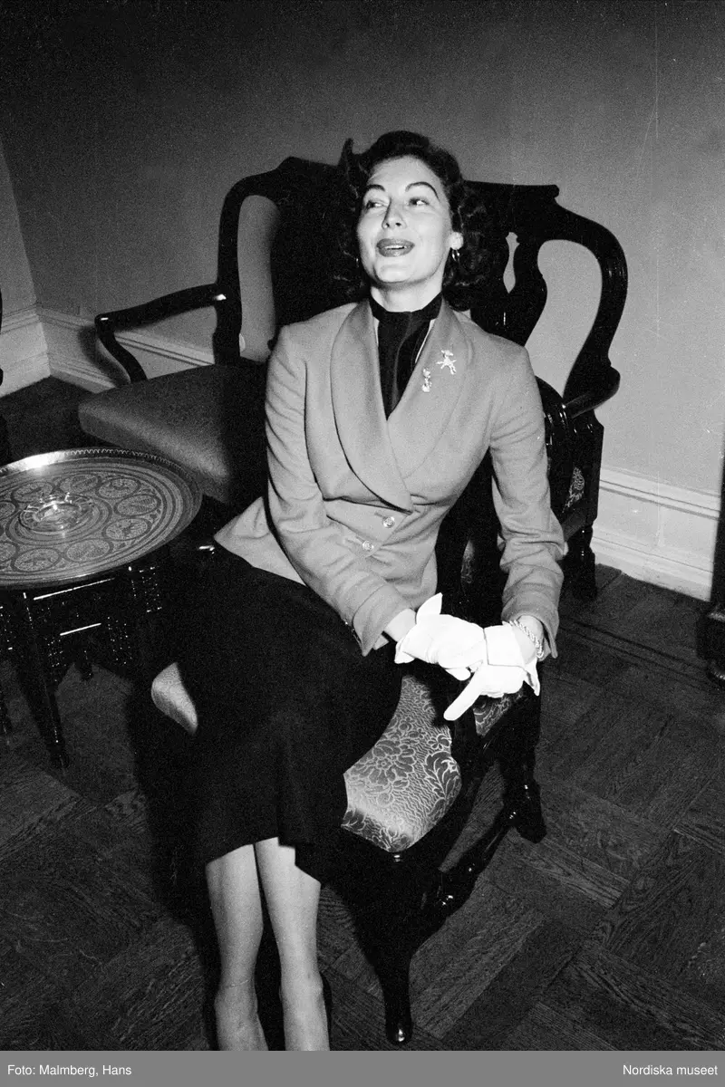  Ava Gardner sitter i en stol. Från reportage om Frank Sinatra på turné i Sverige. Folkets park.