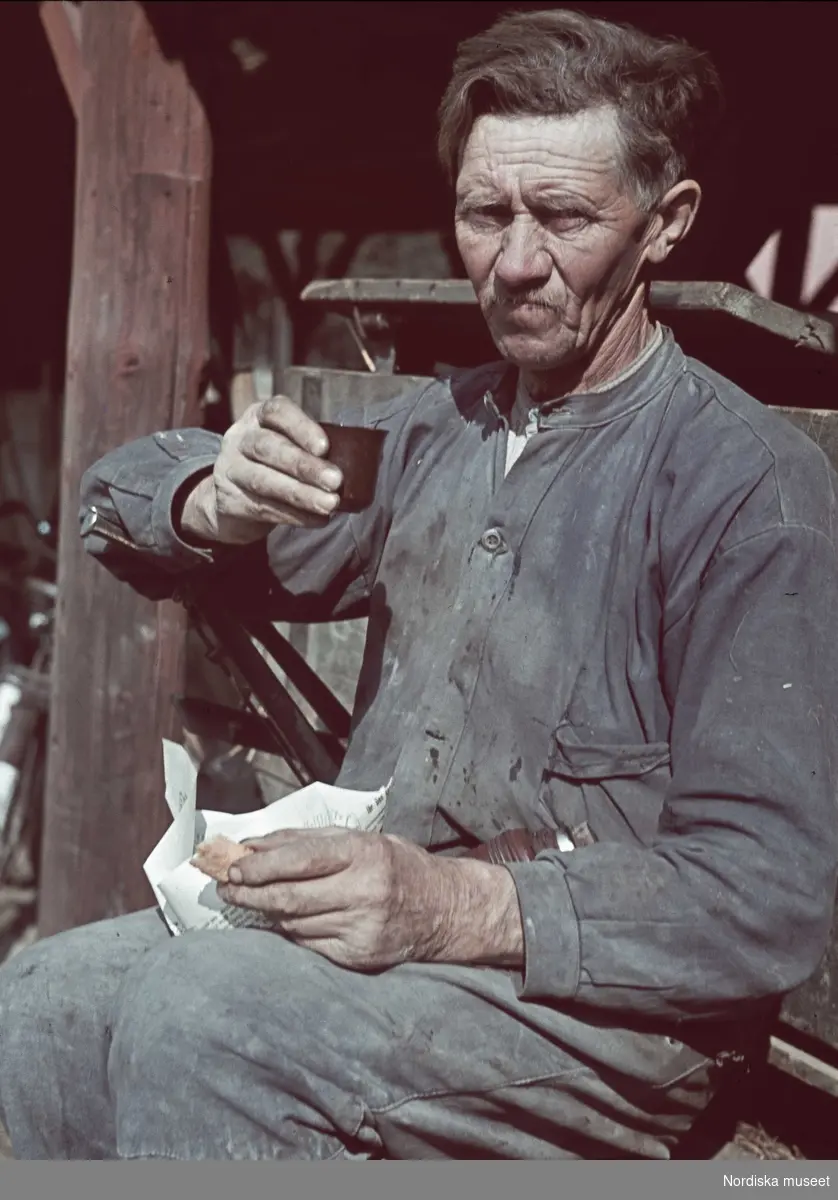 En man tar matrast. Han dricker kaffe ut locket till en termos och håller en smörgås i handen.