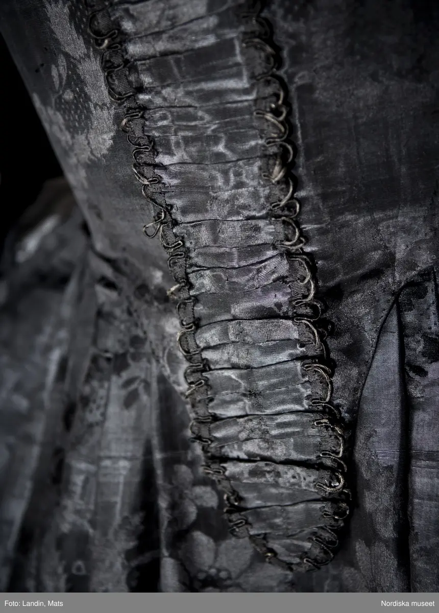 Bruddräkt, svenska dräkten. Av svart mönstrat siden. Buren 1 januari 1780 av Sofia Lovisa Brüch. Nordiska museet inv nr 192119.