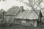 Granet, Hinneryds socken, Småland. Loftstuga från täppan. Stugans lägre del är täckt med brädor och s k bakar (ytor eller utrännare). Den högre delen är täckt med spån. Troligen har även den lägre delen tidigare varit spåntäckt, men taket har förmodligen tätats med spillvirket från en såg när spånorna tjänat ut.