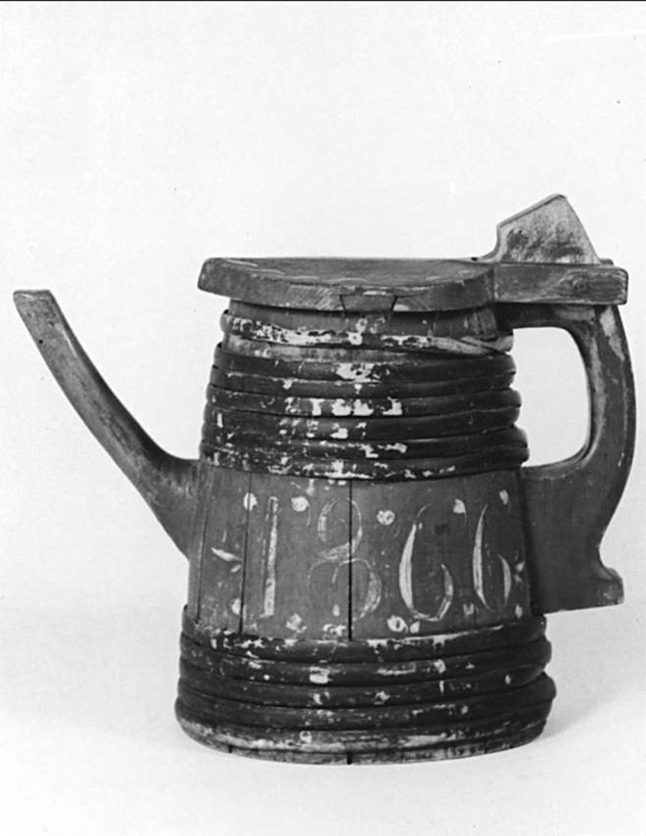 Pipkanna av trä. Röd med svartbruna band. Vit dekor och årtalet 1866.
