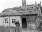 Lovisa Jansdotter framför sitt torp på gränsen mellan Litslena by och Hällby gård, Litslena socken, Uppland, 1910-tal