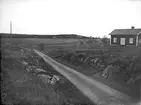 Landskapsvy med bostadshus och väg i Vittinge socken, Uppland i maj 1922