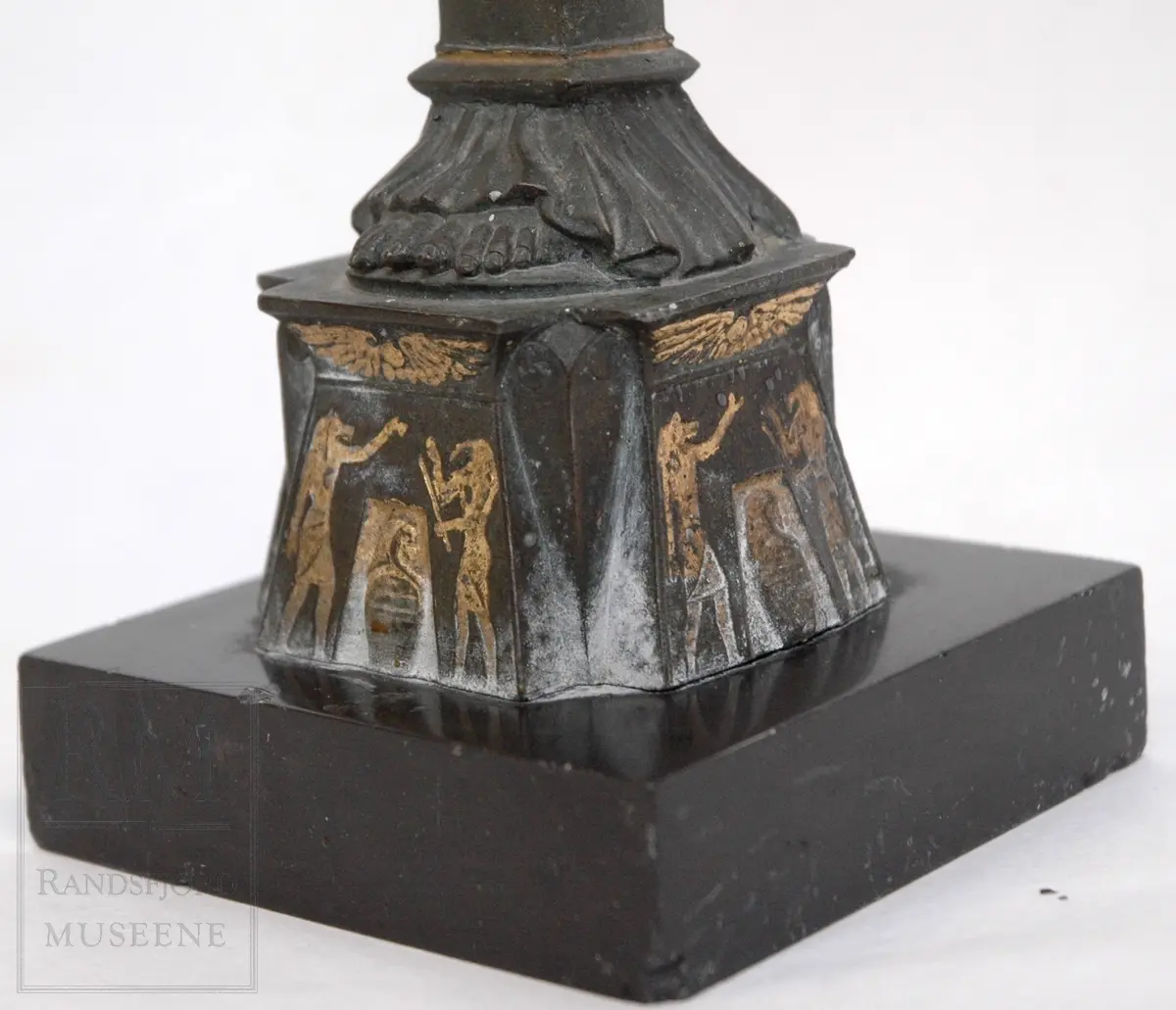 Kvinnefigur på sokkel, med ett barn i hver arm. Barna holder hvert sitt horn (?) med lyseholder. Noe forgylling. Løse lysmansjetter. b) mangler sokkel.