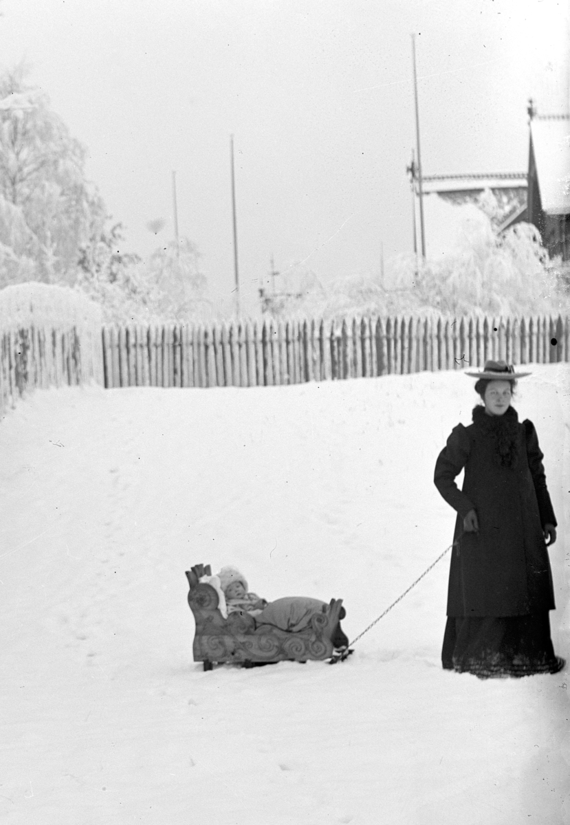 Hamar,  St. Olavs gate 66, Johanne Alhaug (1886-1979) med sin datter på en kjelke utenfor Holmsgården: enten Eva Alhaug (1909-) eller Margit Alhaug (1904-)