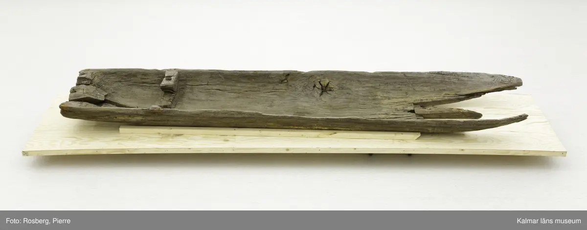 KLM 45167. Båt, stockbåt. Av urholkad trädstam. Huggen i ett stycke. Rektangulärt, något fallande tvärsnitt. Sprucken i fyra delar men de kan lätt sättas samman. I aktern en köl som saknar partier. Kölen sträcker sig fram mot toften, sittbrädan, i båtens akterdel. I toften ett borrat hål. I bottnen på styrbord sida ett hål med en träplugg i, likaså babord reling har ett sådant hål. Fören har blivit lagad vid någon tid och ett stort stycke saknas. I akterns ände tre borrade hål men träpinnar i. Små borrade hål och lagningar med järndobbar, framför allt i fören.