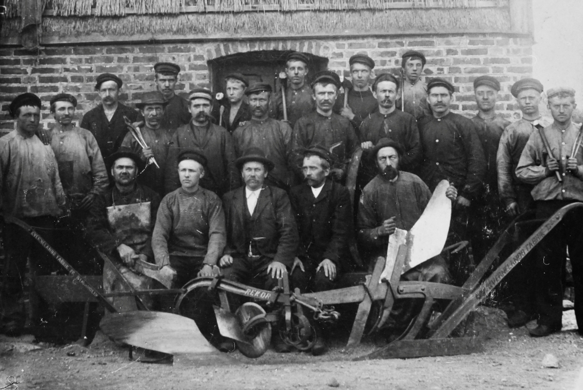 Ansatte til Kvernelands Fabrikk rundt 1910 utenfor "Storhuset", bak f.v. Benjamin Stavnem, Alfred Bolme, Ukjent, Ukjent, Ukjent, Bredenbekk; i midten f.v. Bertel Heskje, Jonas Moi, F. A. Underhaug, Albret Tjemsland, Jakob Eide, Olaus Stensland, Lars Lima, Jon Stangeland, Ukjent, Per Orstad, Ivar Mæland; foran sittende: Nils Aarstad, Gabriel Kverneland, O.G. Kverneland, Lars Ohma, Severin Kyllingstad