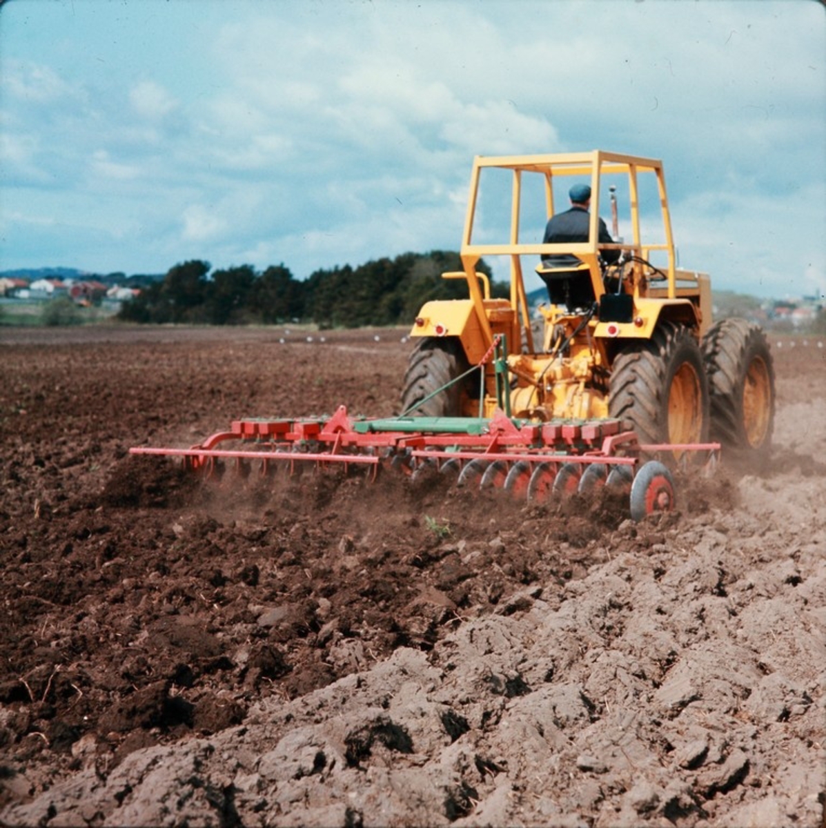 Harving med 40-skålers Skålsvans med ramme av firkantstål, på Sola med stor traktor, sannsynligvis Stig Svensson på traktoren