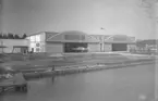 Exteriör av hangar på F 2 Roslagens flygflottilj sett från vattnet, 1935. Brygga, slip, hangar och flygplan