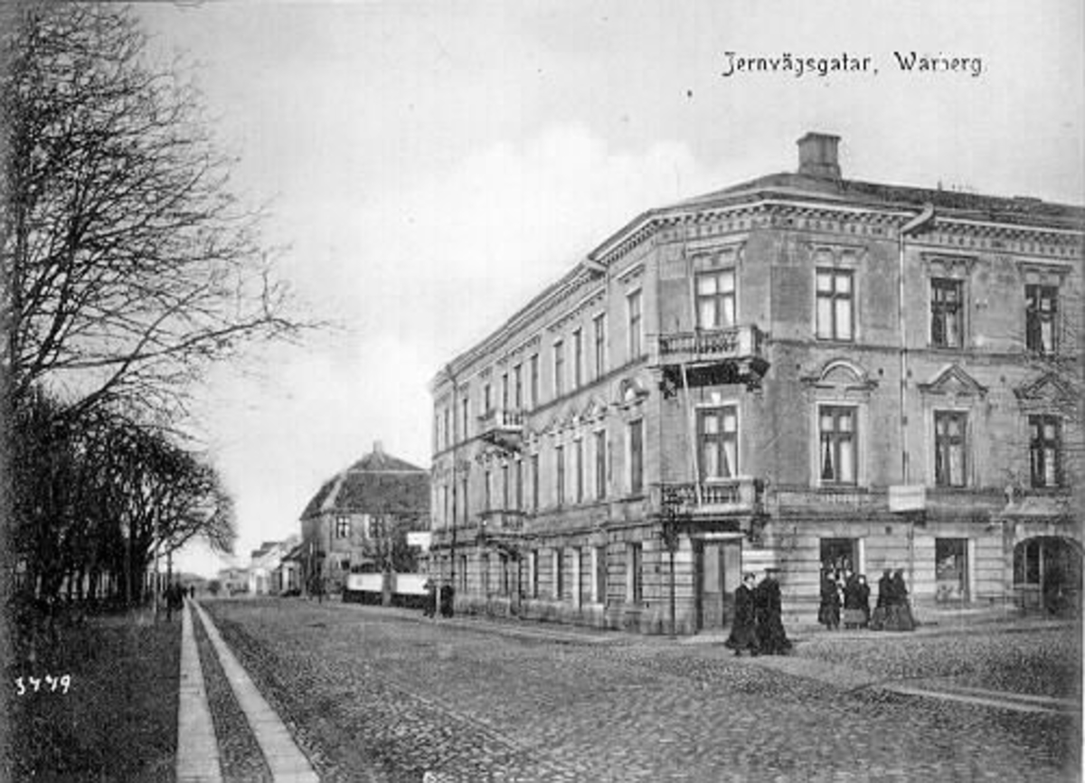 Vykort, "Jernvägsgatan, Warberg". Huset till höger ligger i kvarteret Prosten (nr 7), Västra Vallgatan-Kyrkogatan. Bilden är tagen mot norr. Idag heter gatan Västra Vallgatan.
