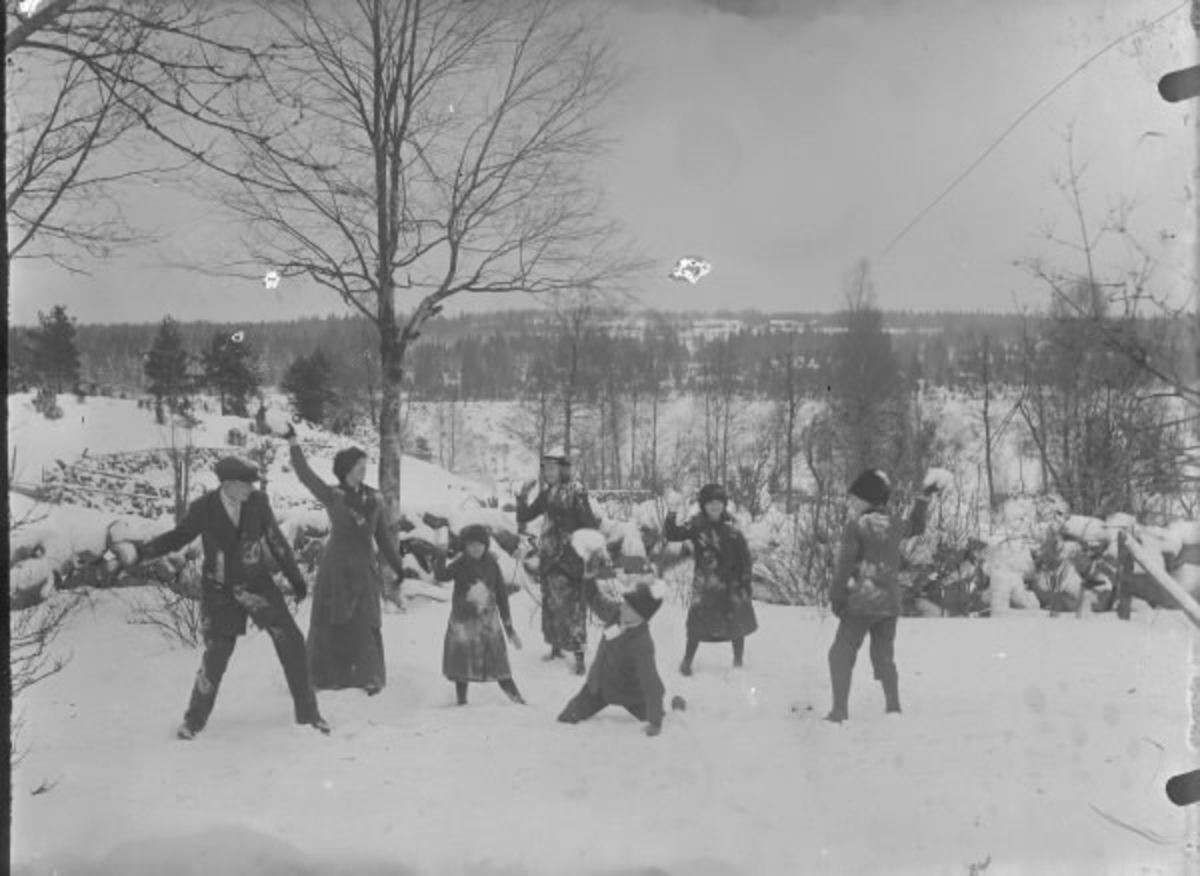 Några barn och ungdomar har snöbollskrig en vinterdag i Drängsered under tidigt 1900-tal. (Se även HB304, HB308)