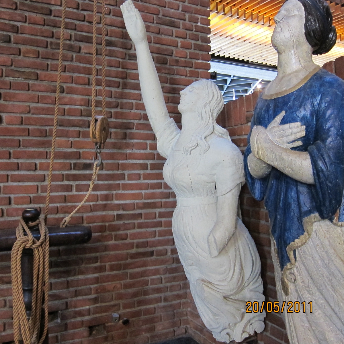 Kvinnefigur med høyre arm hevet, venstre underarm mangler.