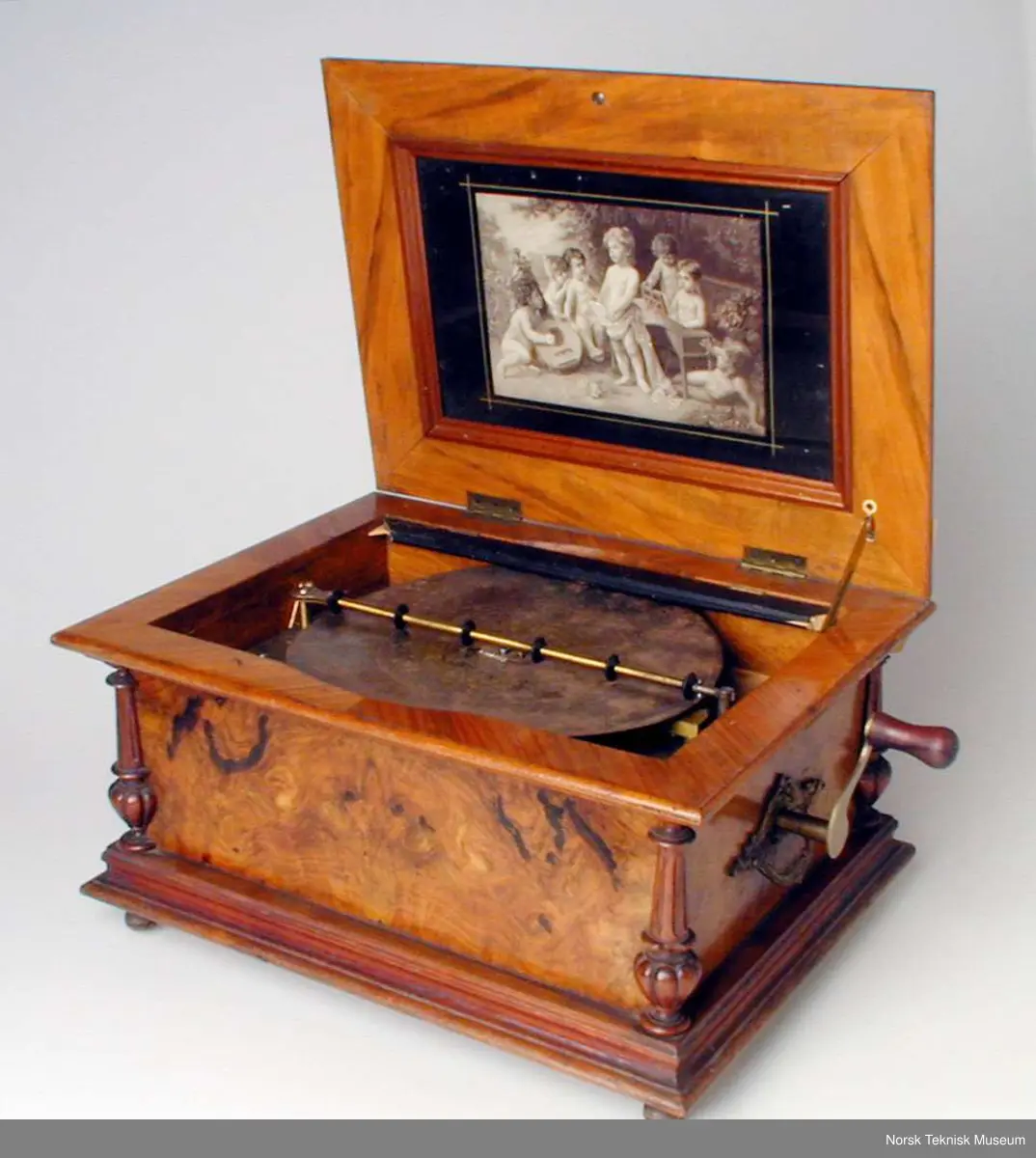 Med en plate: Die Morgenglocken. Nr. 3082. Bilde nr. 6 viser en tilsvarende spilleautomat i god stand. Den viser at det opprinnelig har vært et glasslokk over platen. På den registrerte gjenstanden er bare deler av den sorte rammen som glasset har vært festet i igjen.