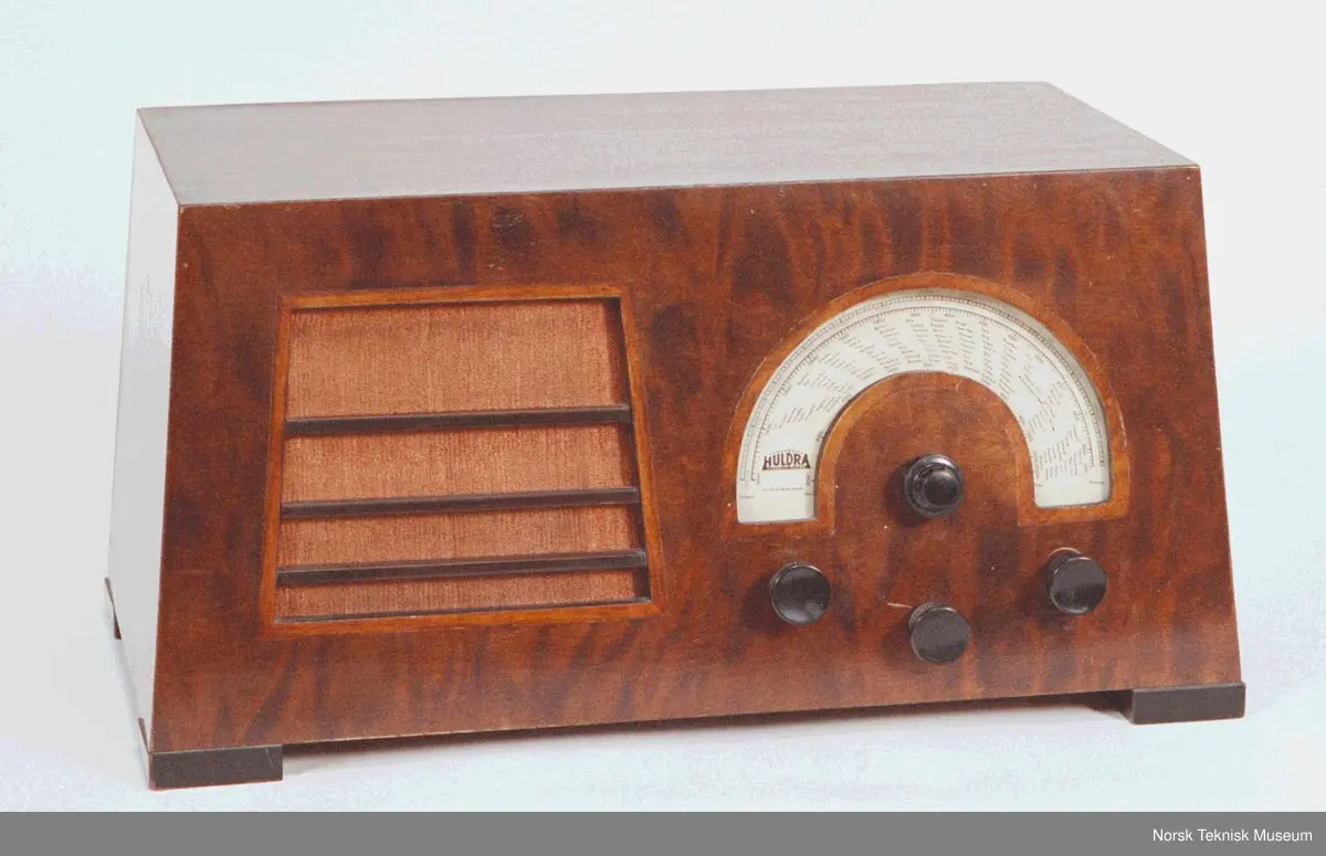 Radio kabinett av polert flammebjerk.
Rørbestykning: AK1, AK1, AF2, AB1, E424N, 2 X E443H, 80 (1 b: AK1, AK1, AF2, AB1, E424N, E443H, E443H, 80)
Høyttaler: Elektrodynamisk, 20 cm. (8")